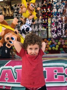 A young child holds a stuffed animal he ostensibly won at a carnival game. 