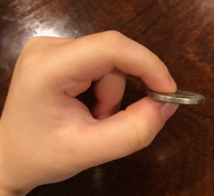 A dime is held between a child's pointer finger and thumb in a pincer grasp.